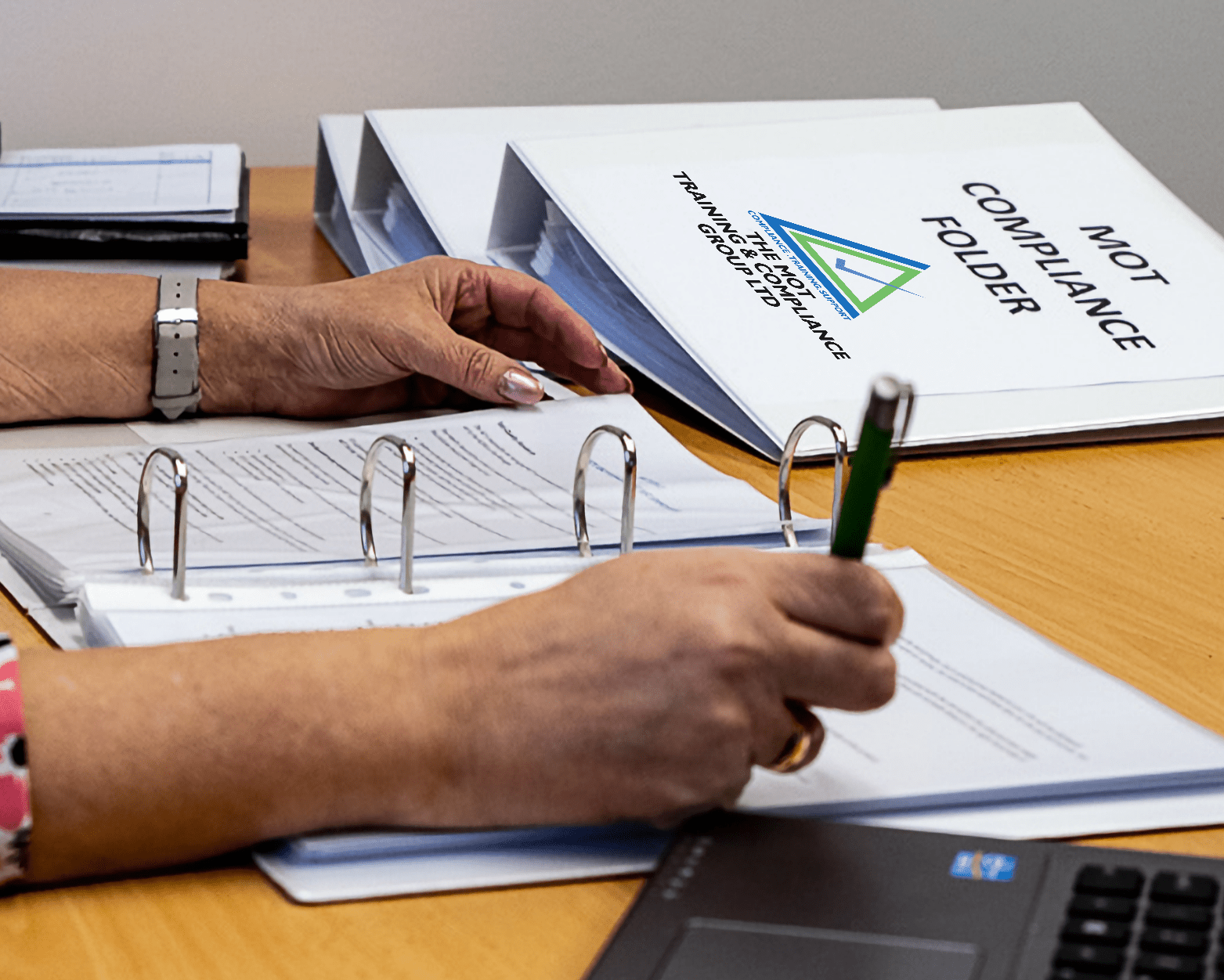 Person's arm with pen completing document in MOT Testing training manual